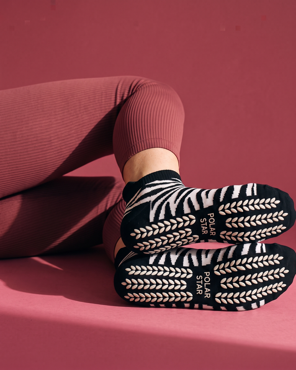 Onyx: solas com padrão zebra, grips de silicone antiderrapantes branco-creme em forma de espiga e logótipo Polar Star em relevo, fundo framboesa