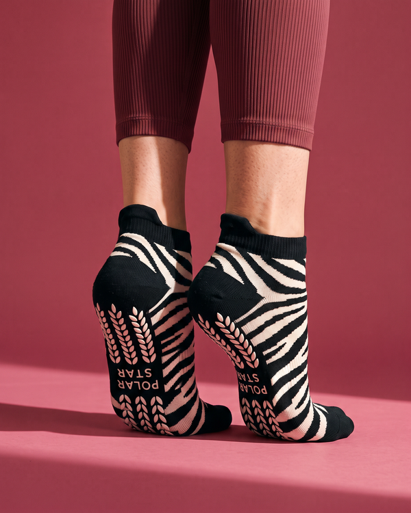 Onyx: meias curtas de Pilates com padrão zebra preto e branco, calçadas, vistas de trás em pontas dos pés, fundo framboesa