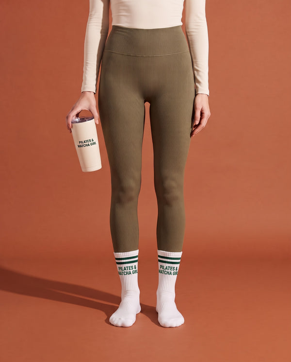 Caixa de oferta Pilates & Matcha: meias Maison Matcha calçadas e caneca Pilates & Matcha Girl na mão, estúdio terracota