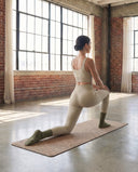 Fente basse sur un tapis en chaussettes de Pilates Lichen vert olive, studio aux murs de briques
